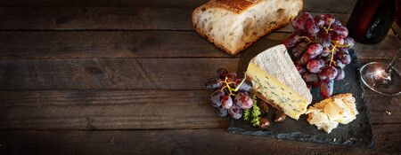 Italian lifestyle with red wine and aromatic cheese on old rustic wooden table. Atmospheric food still life for a gastronomy concept. Horizontal top view with space for text.の写真素材