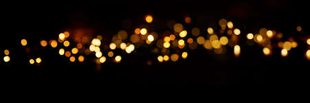 Black background with golden light effects. Horizontal background with blur bokeh effects for christmas time. Special occasion concept with space for text.の写真素材