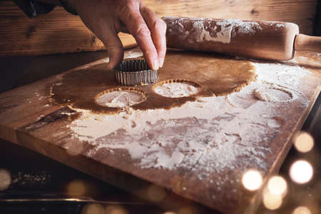 Baking utensils and dough for christmas cookies on wooden cutting board with golden bokeh. Background for christmas baking. Short depth of field with space for decorations and text.の写真素材