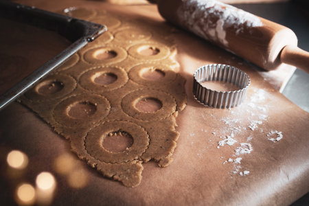 Baking traditional linzer cookies with strawberry jam. Christmas background with golden bokeh and...