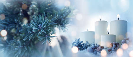 Candles with fir branches in the winter sunlight. Frozen christmas decoration with festive bokeh. Background for christmas and advent concepts with space for text.の写真素材