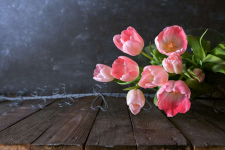 Atmospheric mothers day still life with pink tulips on dark vintage background. Space for text.の写真素材