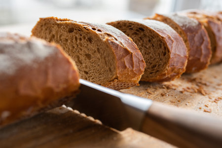 Freshly cut crusty baguette on a wooden cutting board. Sliced traditional french bread. Close-up...