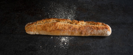 Fresh crispy french baguette on black background. Atmospheric food photography with space for text.
