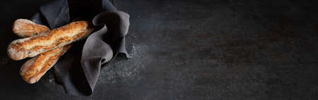 Fresh crispy french baguette on black background. Atmospheric food photography with space for text.の写真素材