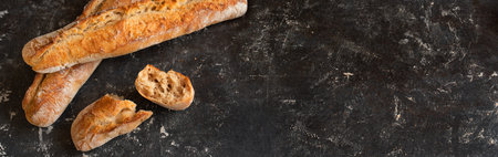 Fresh crispy french baguette on black background. Atmospheric food photography with space for text.
