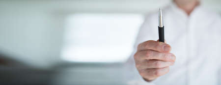 Hands communicate and present in everyday office life with a pen and smart phone. Office scene with short depth of field.の写真素材