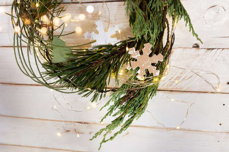 Christmas decoration with pine wreath on white vintage planks and luminous bokeh. Background for greetings with space for text.の写真素材