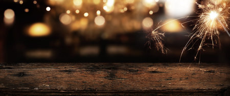 Rustic wooden counter with golden bokeh and sparkler in a dark background.の写真素材