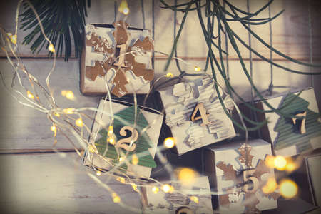 Homemade small carton boxes for advent surbrises with fairy light. Hanging vintage advent calendar made of cardboard for a environmentally conscious christmas. Close-up.の写真素材