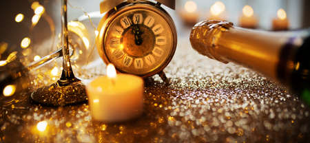 New year countdown with champagner on gold glittering surface with candlelight and bokeh, horizontal background with short depth of field for new year congratulations.の写真素材