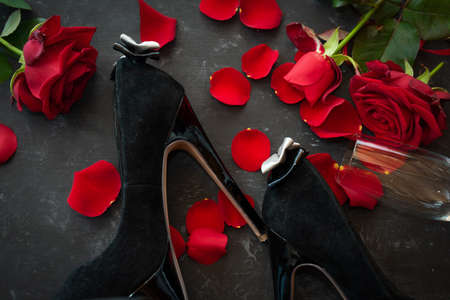Romantic valentines day rendezvous with red roses and black stilettos. Background for love and special moments. top viewの写真素材