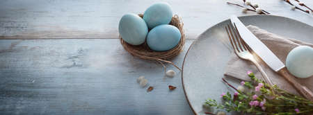 Easter breakfast decoration with spring flowers on bright wood. Horizontal easter background with space for text.の写真素材