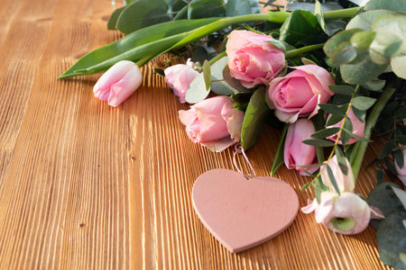 Pink bouquet with heart shape on wood. Background for mother's day greetings. Close-up with short...