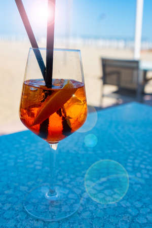 Glass of aperol spritz cocktail on sunny beach. Vertical close-up with short depth of field.の写真素材