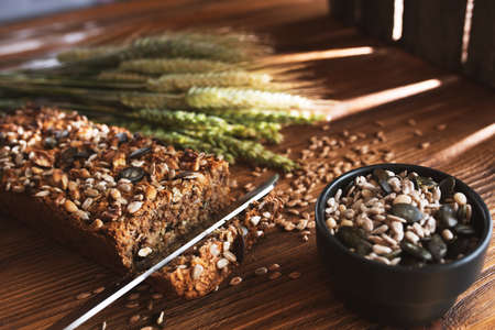 Homemade grain bread and ears of corn on wood with light reflections. Short depth of field.の写真素材