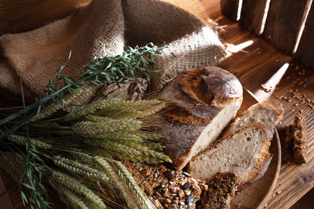 Different sorts of fresh homemade bread and ears of corn on wood with light reflections. Short depth...
