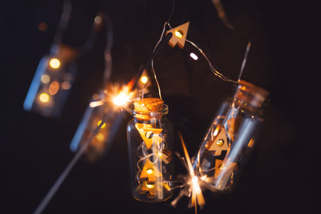 Garland of christmas lights on dark night sky. Illuminated string of lights in glass cylinders with...