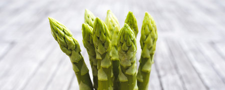 Fresh green asparagus tips on rustic gray wooden planks. Close-up with short depth of field. Background for healthy gastronomy with space for text.の写真素材