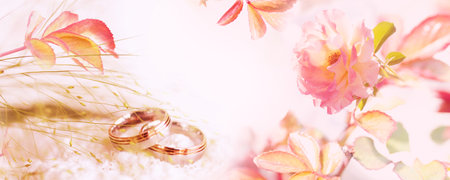 Bright pink rose blossoms with wedding rings. Tender concept background for wedding banners and invitations cardsの写真素材