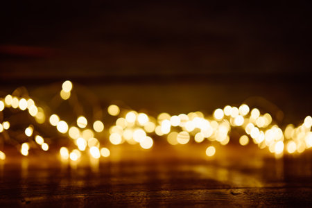 Blurred golden lights on dark wood. Abstract Christmas background with empty wooden table. Use for products decorations.の写真素材