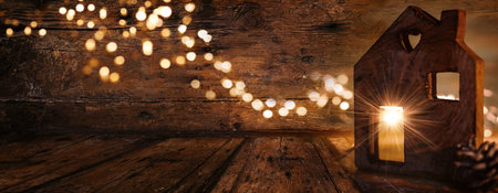 Christmas greeting card with a wooden shape of a house and light rays on old dark wood with golden bokeh. Christmas background with warm glow and dimly lit environment.の写真素材