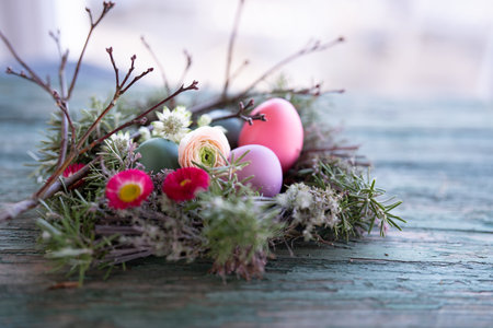 Easter eggs decorated with colorful spring flowers on old rustic wood surface. Background with short depth of field for Easter greetings and space for text.の写真素材