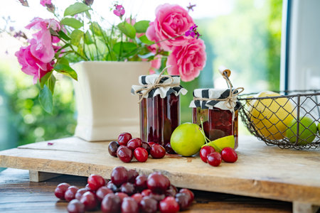 Fresh homemade cherry jam in a jar. Ingredients for preserving fruit on wooden table. Kitchen scene for homemade cooking.の写真素材