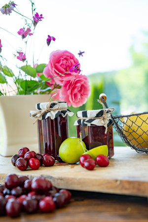 Fresh homemade cherry jam in a jar. Ingredients for preserving fruit on wooden table. Vertical kitchen scene for homemade cooking.の写真素材