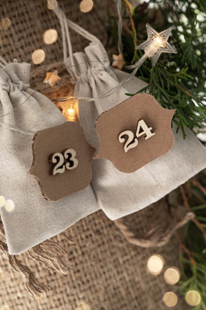 Detail of homemade advent calendar with little surprises in linen bags on rustic burlap. Christmas...