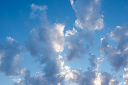 Sunny clear blue sky with white and gray clouds. Seasonal cloudscape. Nature background for environment, climate, and weather forecasting.の写真素材