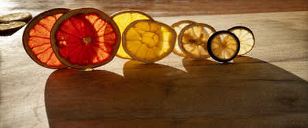 Various dried citrus fruits backlit on wood with shadows. Visible fruit texture with natural patterns for Christmas decorations.の写真素材