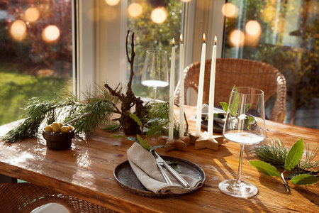 Atmospheric Christmas table decoration in a cozy conservatory with festive bokeh lights. Decorations concept for a Christmas dinner in restaurant.の写真素材