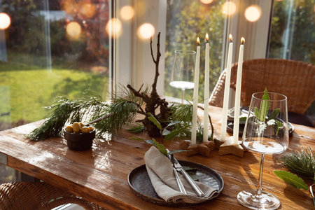 Atmospheric Christmas table decoration in a cozy conservatory with festive bokeh lights. Decorations concept for a Christmas dinner in restaurant.の写真素材