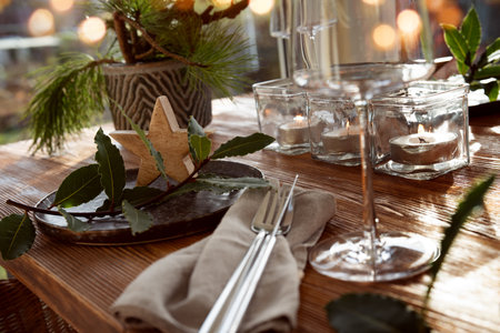 Atmospheric Christmas table decoration in a cozy conservatory with festive bokeh lights. Christmas dinner concept with burning candles in a restaurant. Gastronomy background.の写真素材
