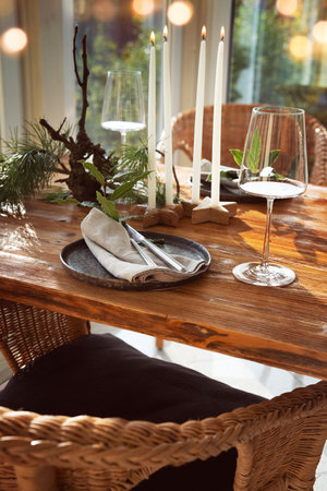 Atmospheric Christmas table decoration in a cozy conservatory with festive bokeh lights. Decorations concept for a Christmas dinner in restaurant.の写真素材