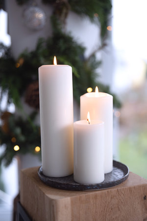Three burning white candles with natural decoration. Vertical Christmas background and short depth of field and space for text.の写真素材