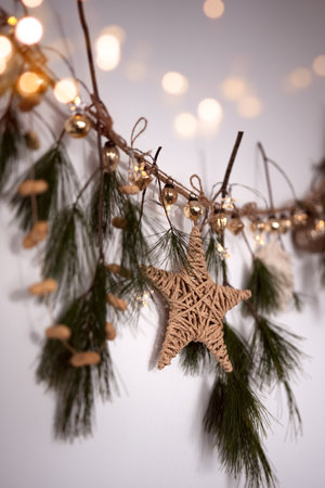 Homemade Christmas decoration with pine branches, golden baubles, poinsettia, and festive bokeh lights. Christmas garland made with renewable materials.の写真素材