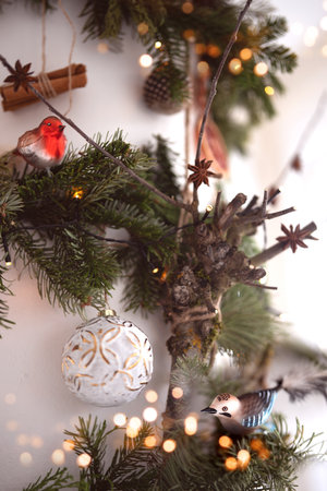 Blue and a red glass bird ornament on a Christmas decoration with blurred bokeh lights. Festive decoration for Christmas greeting cards and banners. Vertical background with shallow depth of field.の写真素材