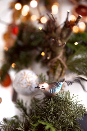Blue glass bird ornament on a Christmas decoration with blurred bokeh lights. Festive decoration for Christmas greeting cards and banners. Vertical background with shallow depth of field.の写真素材