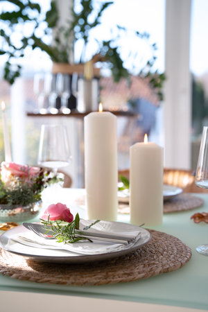 Wedding table decorated with pink roses. Festive set table for a wedding dinner. Bright, elegant restaurant background. Vertical close-up with short depth of field.の写真素材