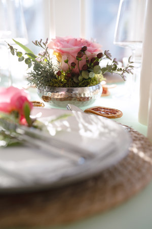 Wedding table decorated with pink roses. Festive set table for a wedding dinner. Bright, elegant restaurant background. Vertical close-up with short depth of field.の写真素材