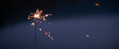 Close-up of a burning sparkler in the evening dusk. Horizontal background for Christmas and New...