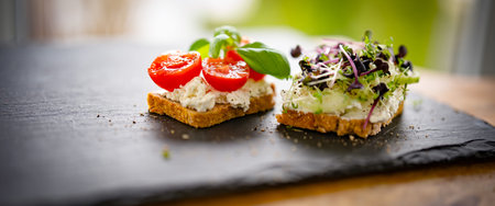 Healthy breakfast bread with cream cheese, cherry tomatoes, basil, cucumber, and fresh cress on a...