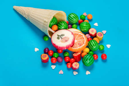 Wafer cone and scattered candies with lollipops on blue backgroundの写真素材