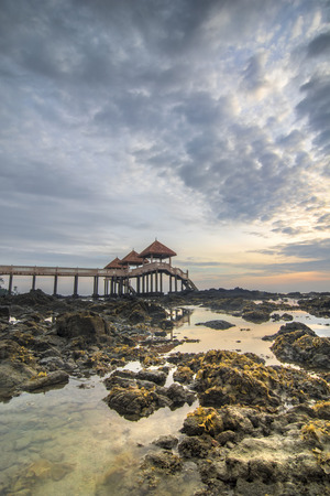 rocky beach and mossy at jetty Tanjung Balau on cloudy sunriseの写真素材