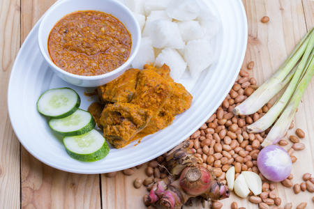 Chicken Rendang is popular dishes in Malaysia, with onion, peanut and lemongrass as decoration on wooden tableの写真素材