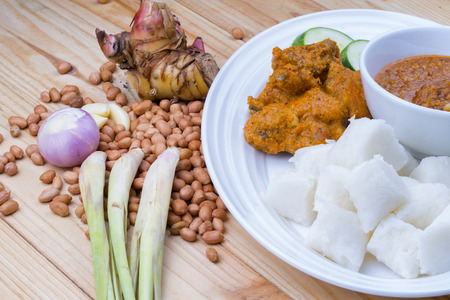 Chicken Rendang is popular dishes in Malaysia, with onion, peanut and lemongrass as decoration on wooden tableの写真素材