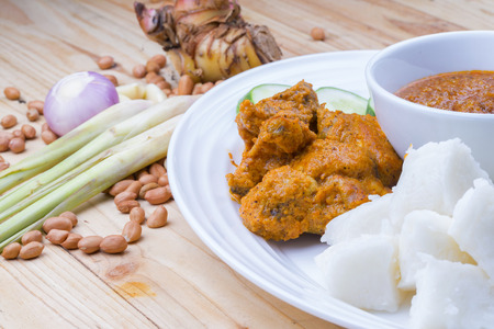 Chicken Rendang is popular dishes in Malaysia, with onion, peanut and lemongrass as decoration on wooden tableの写真素材