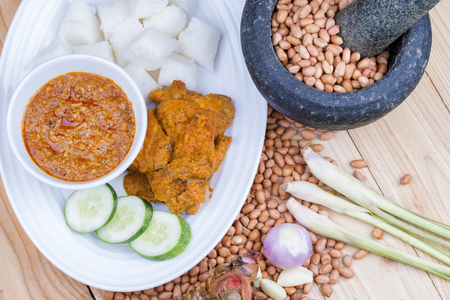 Chicken Rendang is popular dishes in Malaysia, with onion, peanut and lemongrass as decoration on wooden tableの写真素材